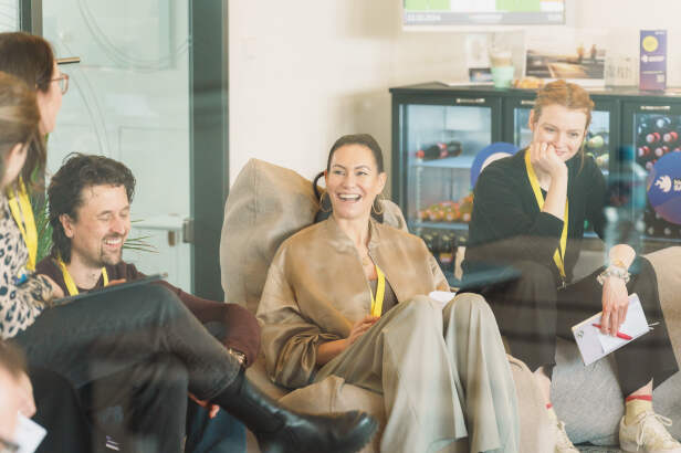 Frau sitzt zwischen anderen Menschen und lacht